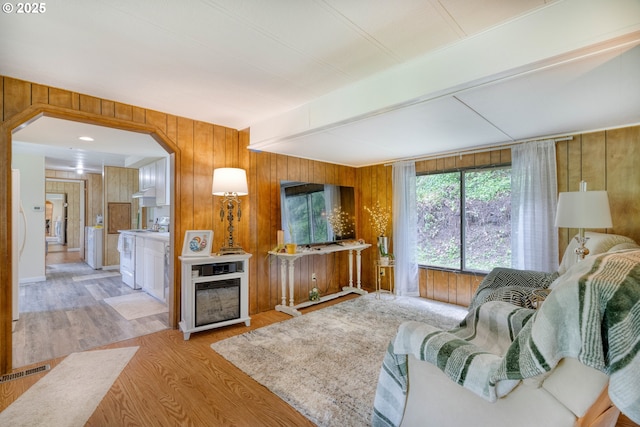 living room featuring wood finished floors, beamed ceiling, and wooden walls