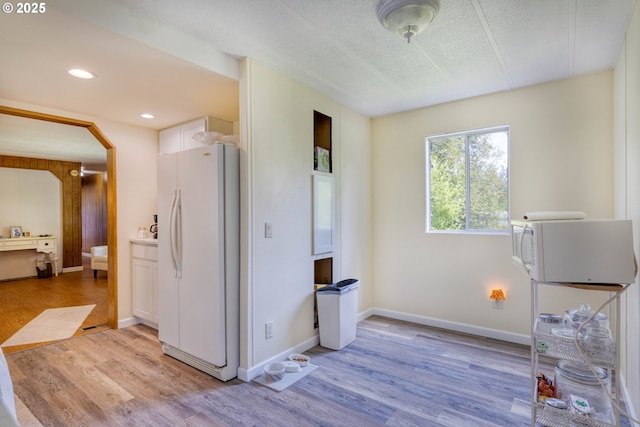 miscellaneous room featuring light wood-style flooring, arched walkways, baseboards, recessed lighting, and a textured ceiling