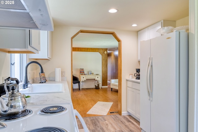 kitchen featuring freestanding refrigerator, light countertops, light wood-style flooring, white cabinetry, and a sink