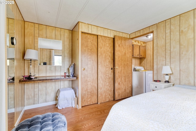 bedroom with washer and clothes dryer, wood walls, and wood finished floors