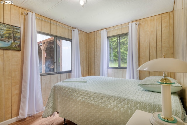 bedroom with wood walls and wood finished floors