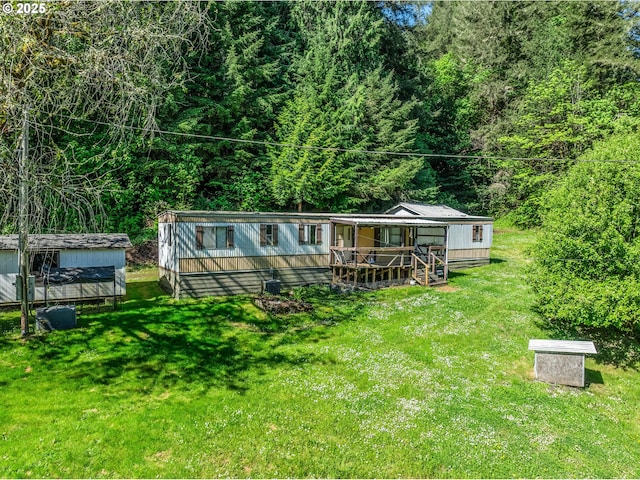 back of house with a lawn, a shed, and a view of trees