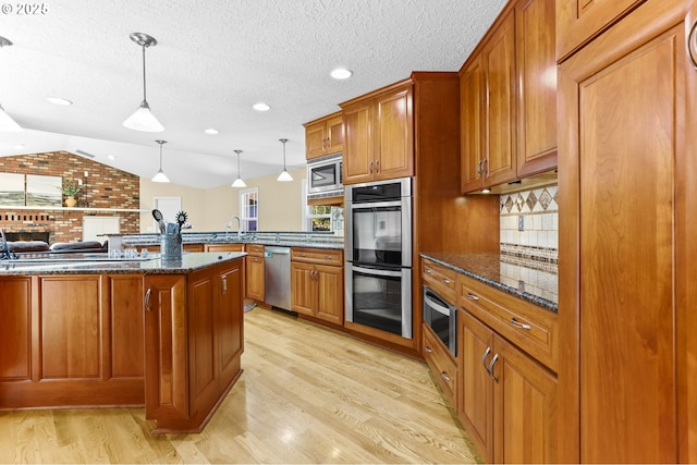 37330 SE Dodge Park Blvd, Boring, OR 97009 - kitchen with stainless steel appliances, brown cabinets, a peninsula, light wood-style flooring, and lofted ceiling
