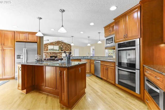 37330 SE Dodge Park Blvd, Boring, OR 97009 - kitchen featuring stainless steel appliances, light wood finished floors, lofted ceiling, dark stone countertops, and brown cabinetry