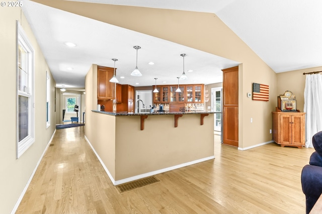 37330 SE Dodge Park Blvd, Boring, OR 97009 - kitchen featuring a breakfast bar area, a peninsula, brown cabinetry, glass insert cabinets, and light wood-style floors