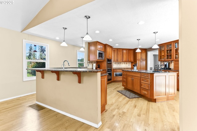 37330 SE Dodge Park Blvd, Boring, OR 97009 - kitchen featuring stainless steel appliances, a kitchen breakfast bar, brown cabinetry, light wood finished floors, and recessed lighting