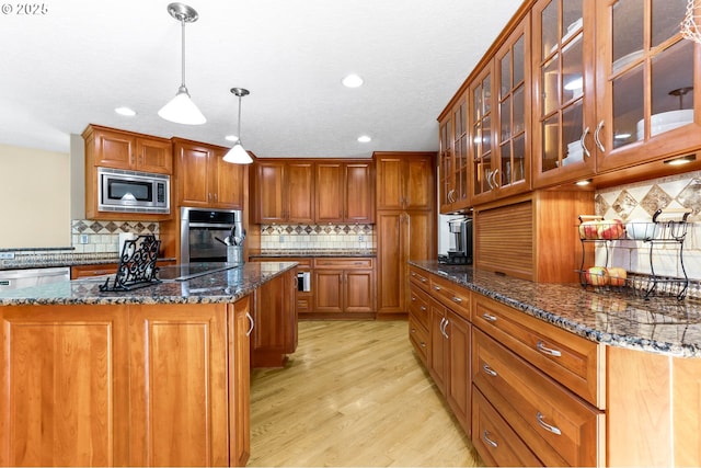 37330 SE Dodge Park Blvd, Boring, OR 97009 - kitchen featuring stainless steel appliances, brown cabinetry, light wood-style flooring, decorative backsplash, and dark stone countertops