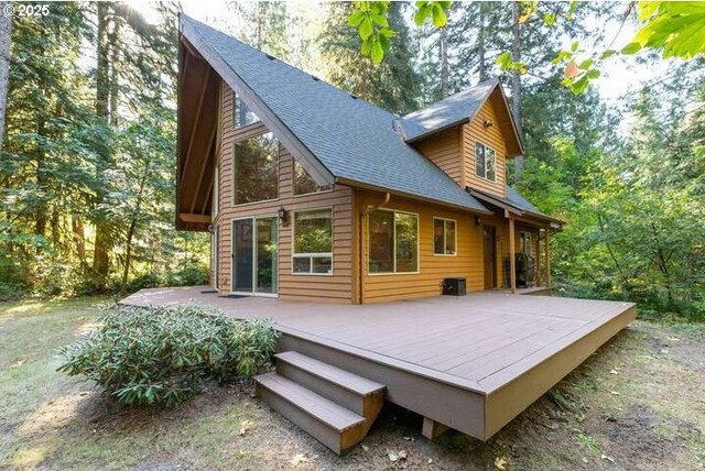 back of house with roof with shingles and a deck