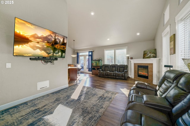 living room with a tiled fireplace, dark wood-type flooring, and french doors