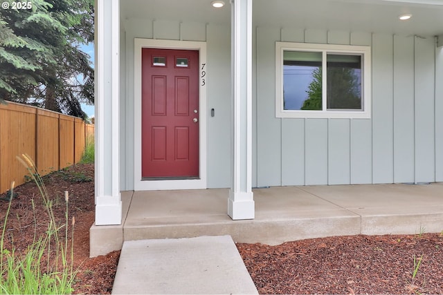 entrance to property featuring fence, board and batten siding, and a porch