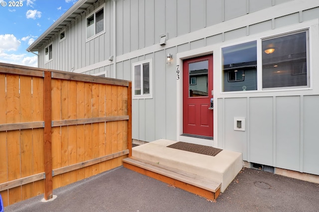entrance to property featuring board and batten siding and fence