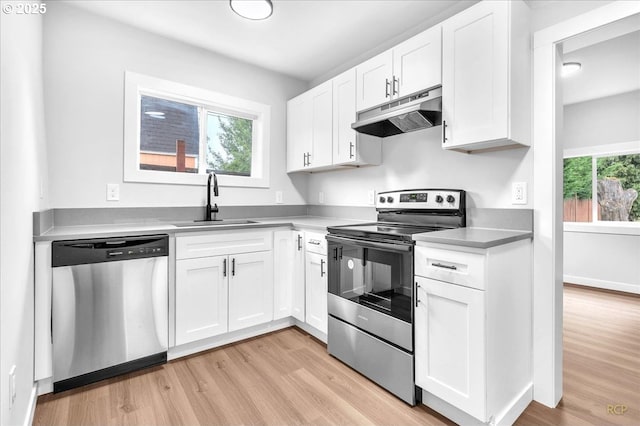 328 18th Ave, Longview, WA 98632 - kitchen with appliances with stainless steel finishes, under cabinet range hood, a sink, light wood-style floors, and white cabinetry