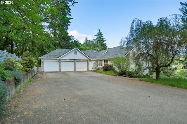 ranch-style house featuring asphalt driveway, a garage, and fence