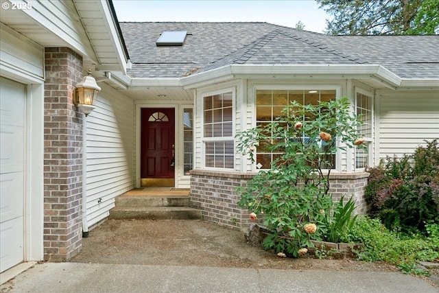 property entrance featuring roof with shingles and brick siding