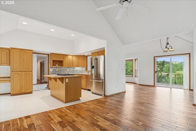 kitchen featuring appliances with stainless steel finishes, open shelves, high vaulted ceiling, a center island, and open floor plan