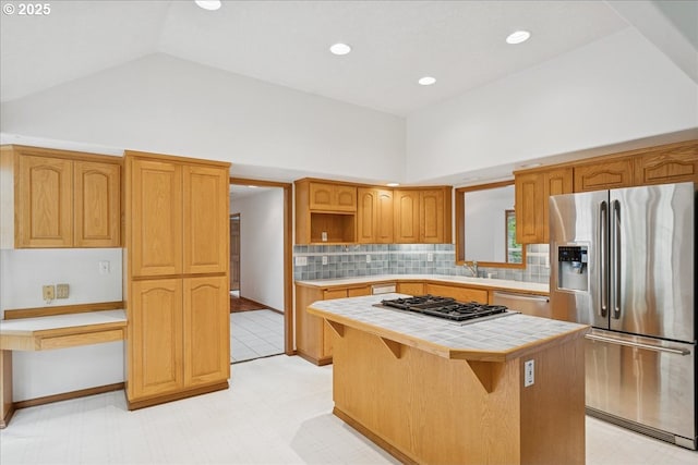 kitchen featuring appliances with stainless steel finishes, tile countertops, a kitchen island, backsplash, and high vaulted ceiling