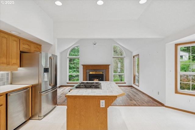 kitchen featuring tile countertops, stainless steel appliances, healthy amount of natural light, ceiling fan, and lofted ceiling