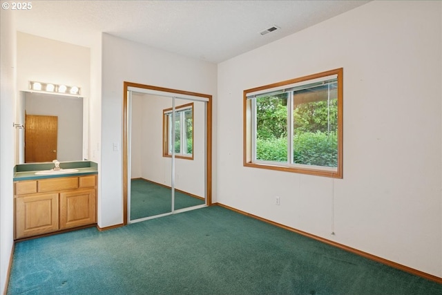 unfurnished bedroom featuring carpet flooring, a sink, baseboards, and a closet