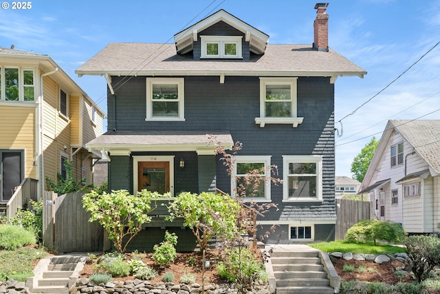 american foursquare style home with a chimney, roof with shingles, fence, a porch, and stairs