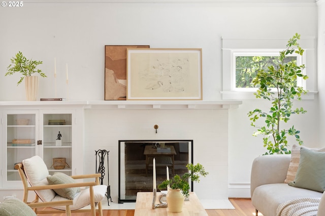 living area with a brick fireplace and wood finished floors