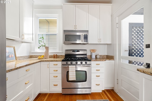 kitchen with stainless steel appliances, light wood-style floors, and white cabinets