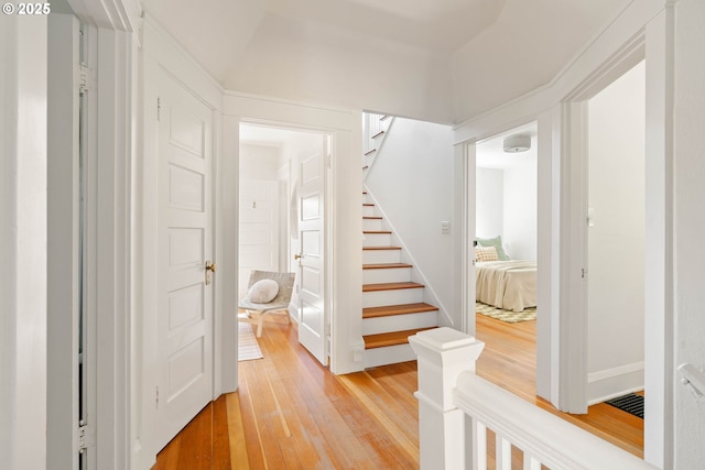 hallway with light wood-type flooring and stairway