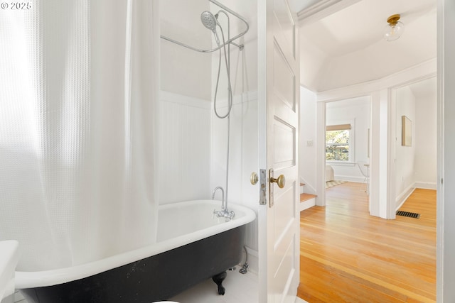 bathroom featuring wood finished floors and shower / tub combo with curtain