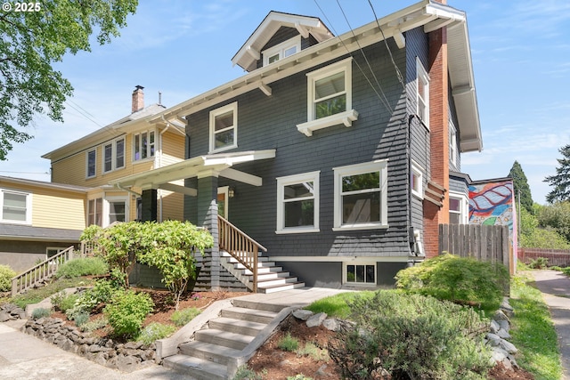 american foursquare style home featuring fence, stairway, and a chimney