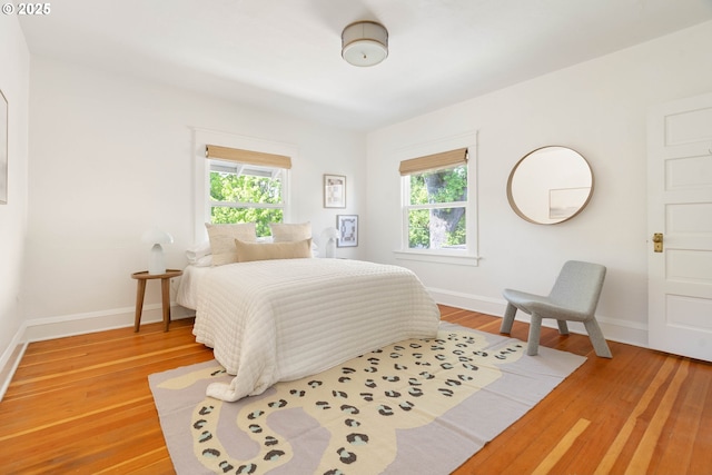 bedroom featuring multiple windows, baseboards, and light wood-style flooring