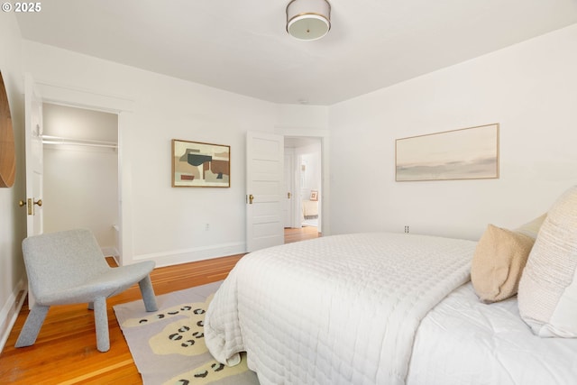 bedroom featuring wood finished floors, baseboards, and a closet