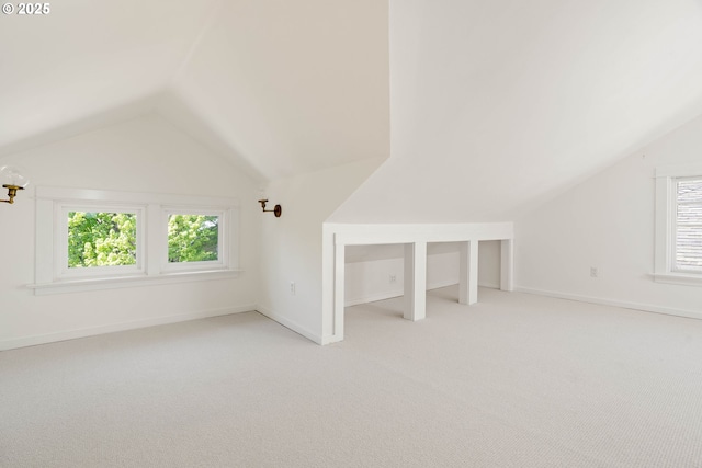 bonus room with vaulted ceiling, plenty of natural light, light colored carpet, and baseboards
