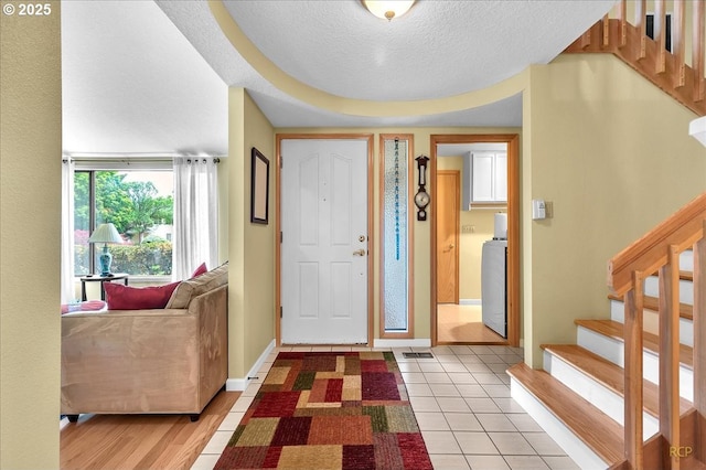 15645 NE Russell Pl, Portland, OR 97230 - foyer entrance with stairs, a textured ceiling, washer / dryer, and light tile patterned floors