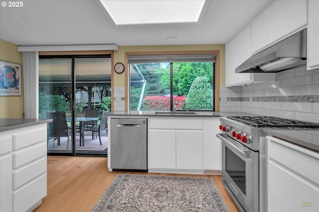 15645 NE Russell Pl, Portland, OR 97230 - kitchen with stainless steel appliances, exhaust hood, white cabinets, and light wood finished floors