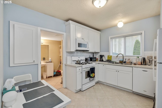 kitchen featuring backsplash, white appliances, sink, and white cabinets