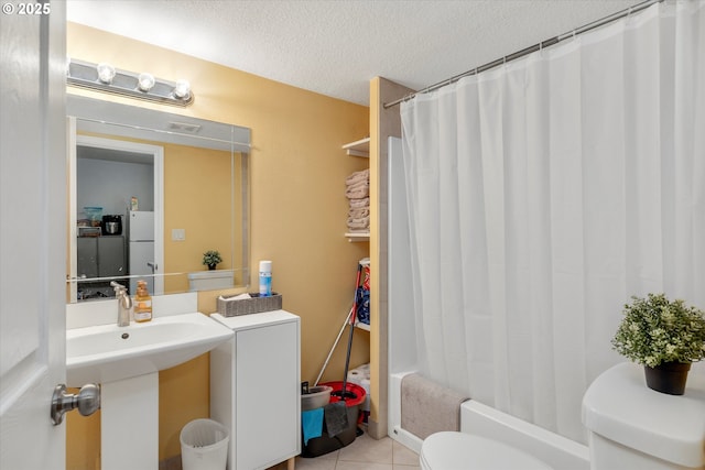 full bathroom with sink, shower / tub combo, toilet, tile patterned floors, and a textured ceiling