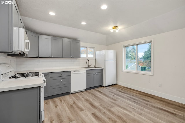 kitchen featuring sink, gray cabinetry, backsplash, and white appliances