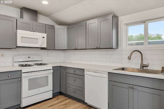 kitchen with gray cabinetry, backsplash, white appliances, and vaulted ceiling