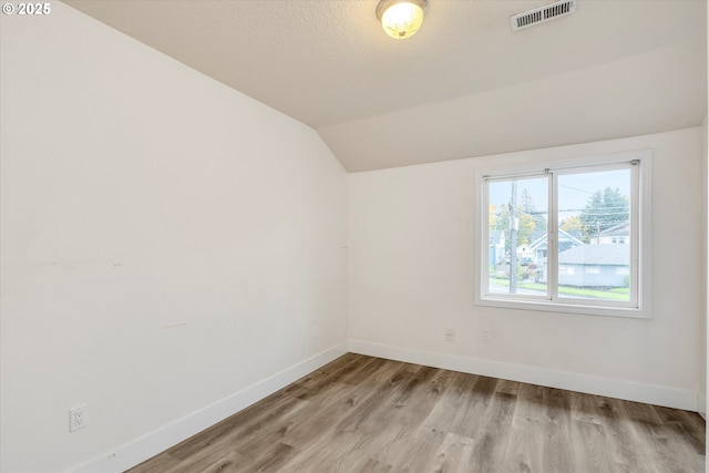 spare room with lofted ceiling and light hardwood / wood-style floors