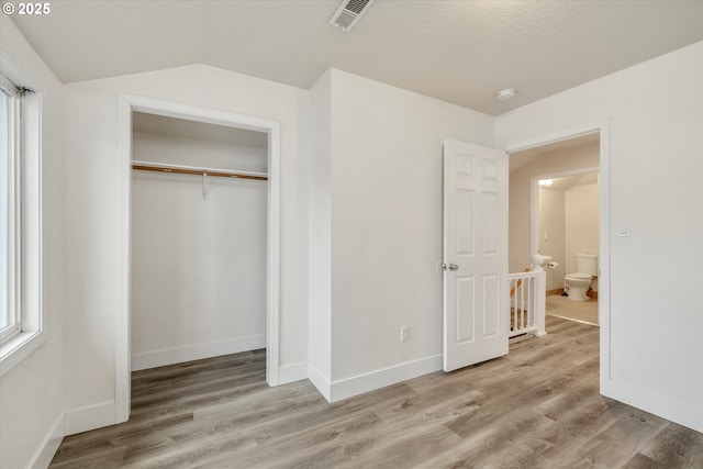 unfurnished bedroom featuring lofted ceiling, hardwood / wood-style floors, and a closet