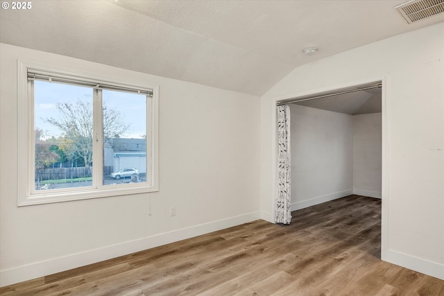 unfurnished bedroom with hardwood / wood-style flooring, vaulted ceiling, and a closet