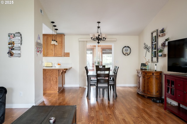 dining area with baseboards, wood finished floors, visible vents, and a chandelier