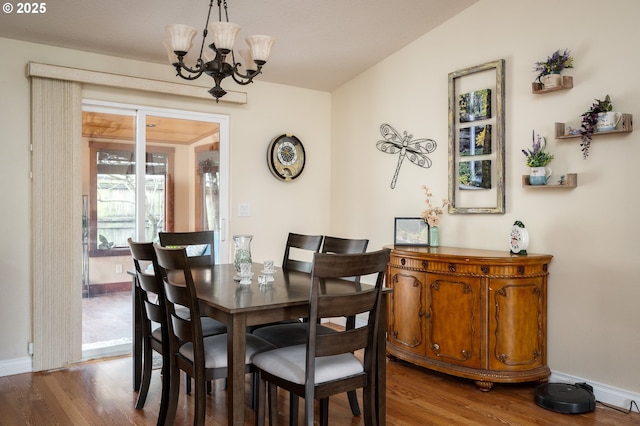 dining space featuring a notable chandelier, baseboards, and wood finished floors