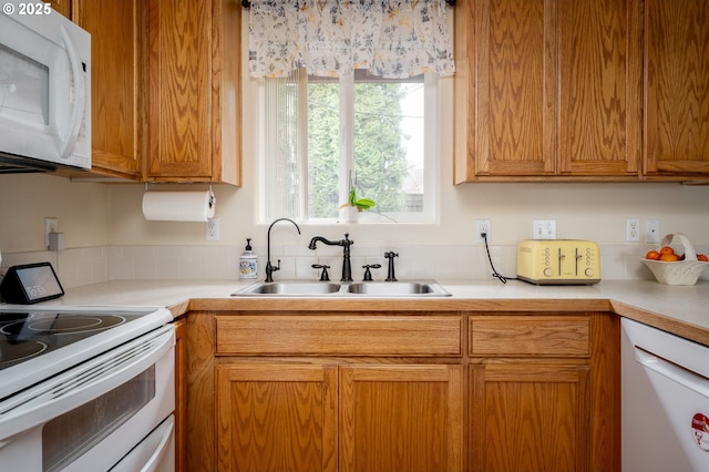 kitchen with a sink, white appliances, and light countertops