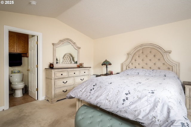 bedroom featuring lofted ceiling, connected bathroom, and light carpet