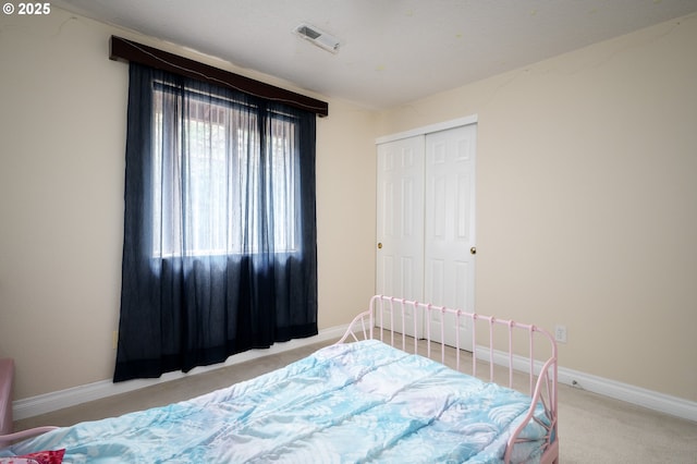 carpeted bedroom featuring baseboards, visible vents, and a closet