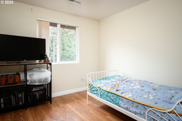 bedroom featuring visible vents, baseboards, and wood finished floors