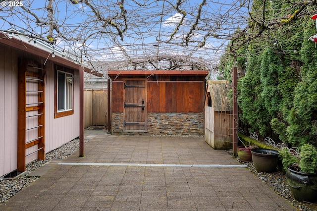 view of patio / terrace featuring an outbuilding, fence, and a shed