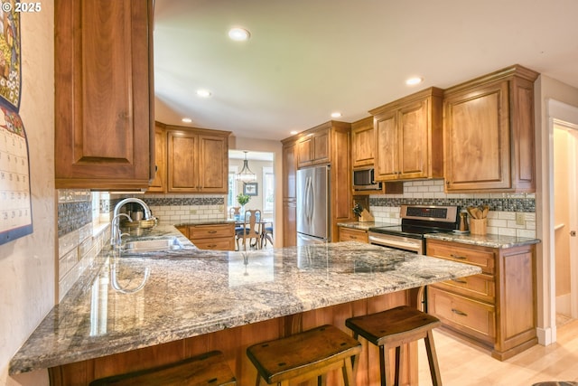 1329 NW Horn Ave, Pendleton, OR 97801 - kitchen featuring appliances with stainless steel finishes, a peninsula, light stone countertops, a sink, and a breakfast bar area