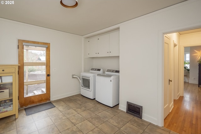 laundry room with cabinets, plenty of natural light, light tile patterned floors, and washing machine and clothes dryer