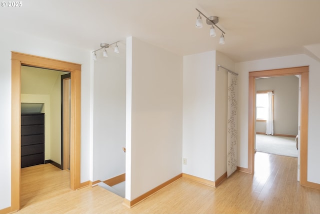 hallway with light hardwood / wood-style floors and rail lighting